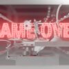 Eine Grafik auf der "GAME OVER" in rot leuchtenden Buchstaben in einem grauen, videospiel-ähnlichen Raum schwebt.