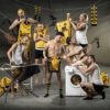 7 men in white-yellow-black underwear pose comedically in a grey, poorly lit room between washing machine, ironing board and clothesline.