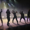 7 Tänzerinnen von hinten angeleuchtet auf einer Bühne