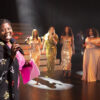 Eine Bühne, groß links im Bild Mable Preach mit Mikro in der Hand, hinter ihr Showtreppe und davor 4 Sängerinnen in goldenen Kleidern