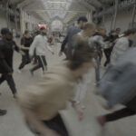 Ein Foto von vielen Menschen, die durch eine große Halle rennen, sie sind durch ihre Bewegungen verschwommen.