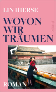Book cover of "Wovon wir Träumen": against a pink background is a photo of a little girl leaning against a parapet and waving at the camera. In the background is a traditional Chinese house.