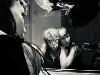 Schwarz-Weiß-Foto von Little Annie und Evilyn Frantic in einem Spiegel, letztere schmiegt sich an Little Annies Rücken.