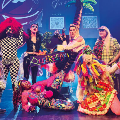 Eine Gruppe von Performer*Innen in bunten Kostümen.