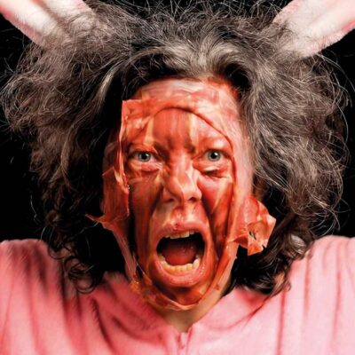 A person with messy hair is wearing a pink bunny costume.