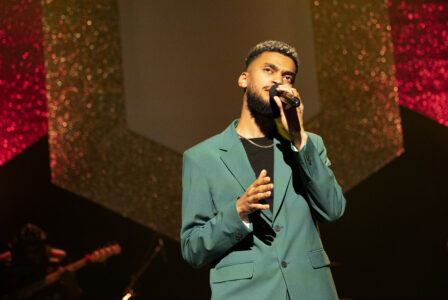 Der Sänger Fahim im grünen Anzug auf der Bühne singend.