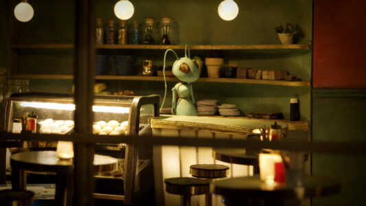 Close-up of the puppet of a green cricket with long, hanging antennae. She stands behind a bistro counter, behind her a shelf of dishes, in front of her a display of pastries.