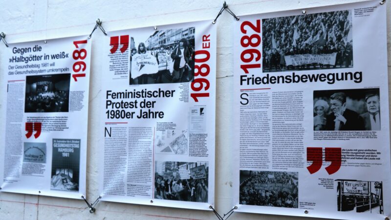 Drei Plakate nebeneinander aufgespannt, darauf Texte und Schwarzweiß-Fotos und die Jahreszahlen 1981, 1980 und 1982 in Rot, lesbar die Überschriften: Feministischer Protest der 1980er Jahre und Friedensbewegung