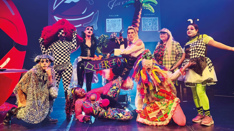Eine Gruppe von Performer*Innen in bunten Kostümen.