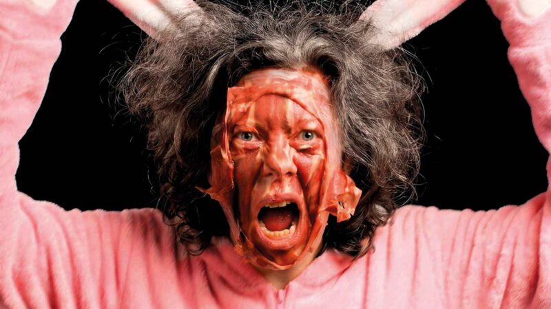 A person with messy hair is wearing a pink bunny costume.